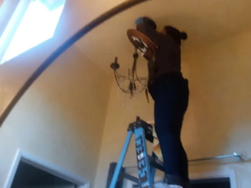 Electrician installing a chandelier in a Fort Meade residence